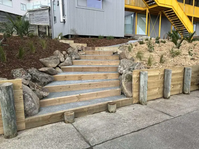 Timber sleeper steps with gravel treads and boulder feature rocks built into a freshly mulched garden bank in Northland, New Zealand
