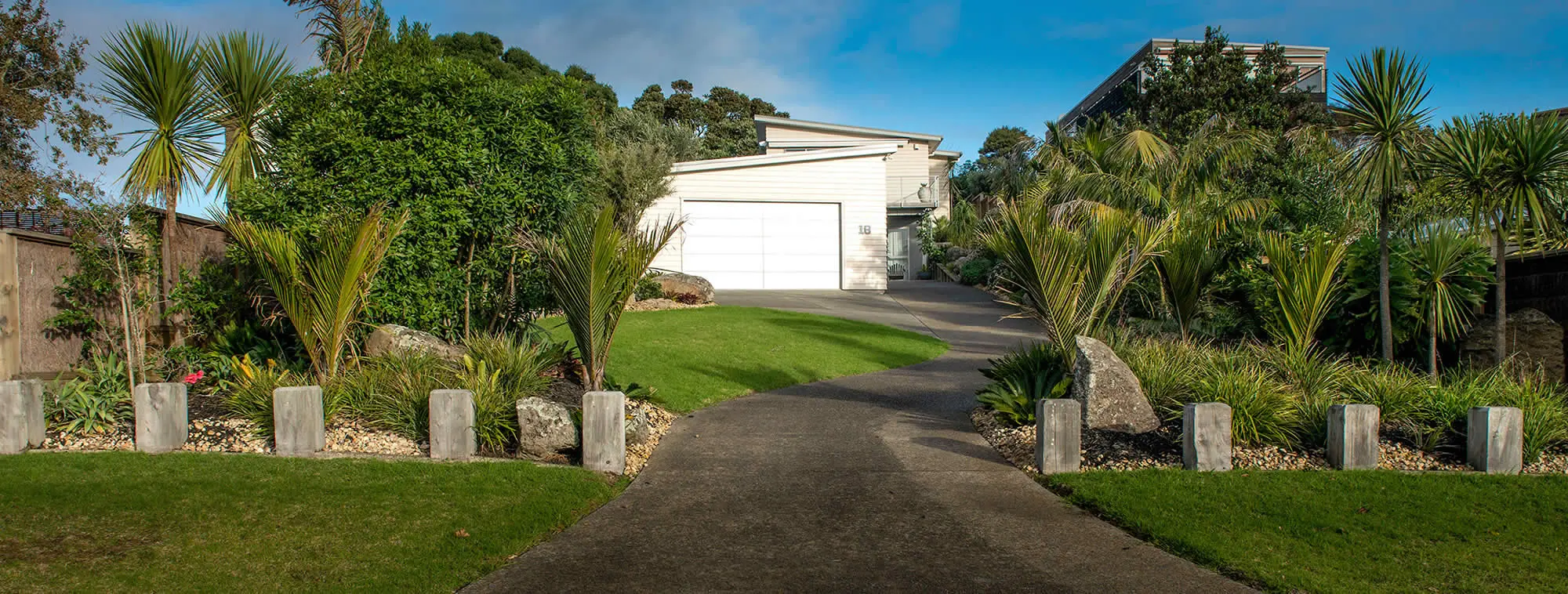 Landscaped garden at front of house with lush lawn and custom designed driveway.